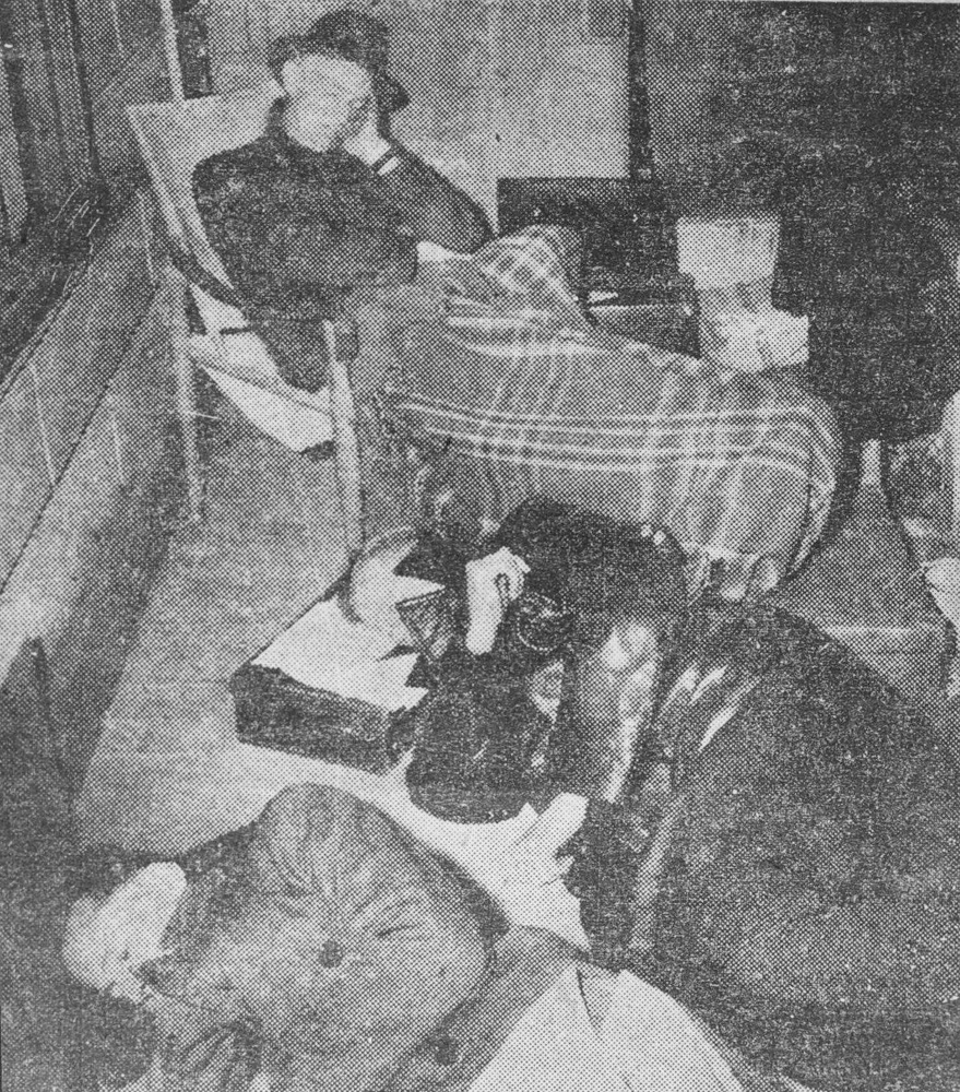 This is a black and white photograph of Father Tucker under a blanket, Frank Coaldrake and Tony Bishop sitting on the verandah of an Armadale house in protest.